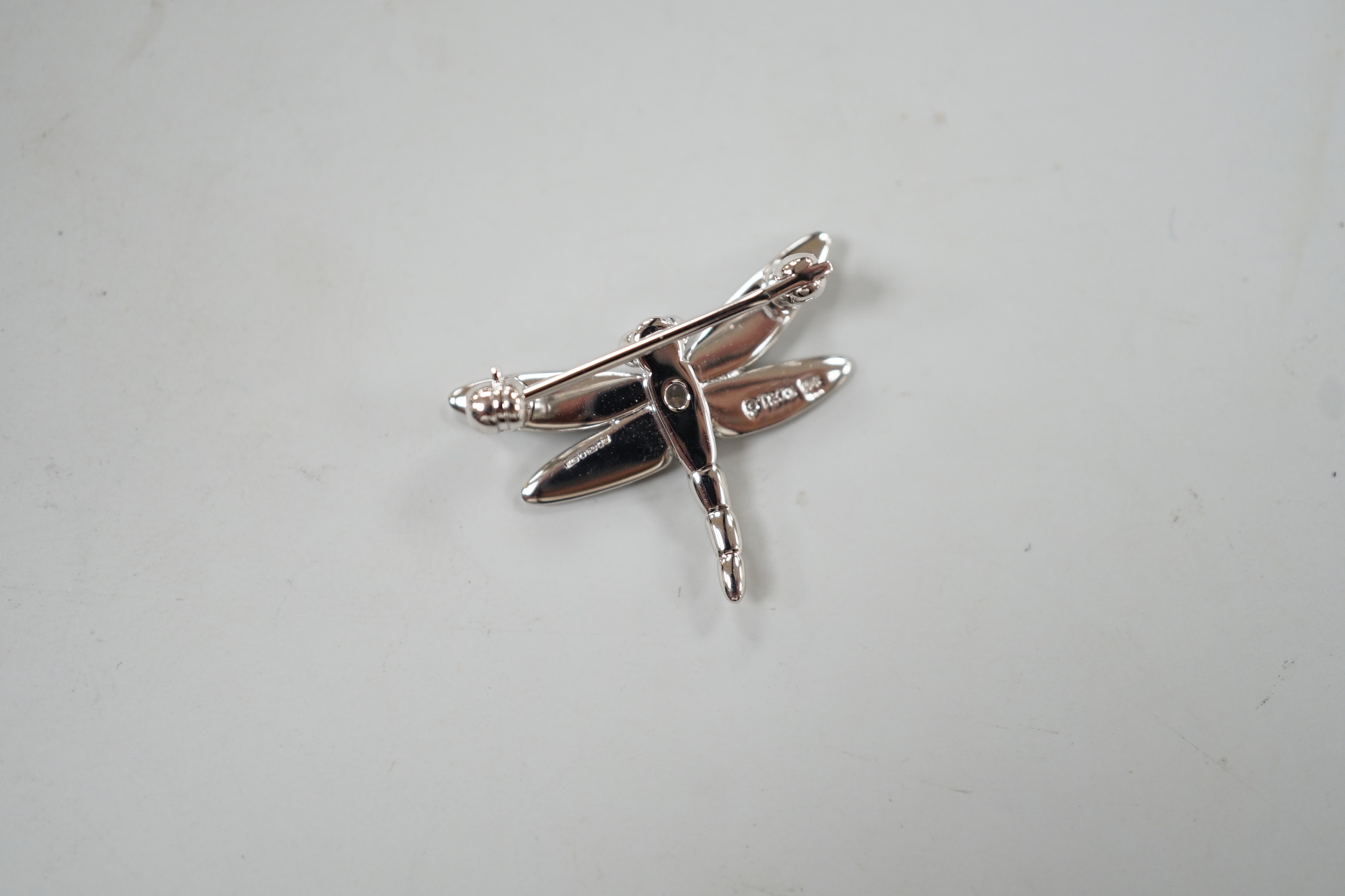 A modern Tiffany & Co 18ct white gold and single stone diamond set dragonfly brooch, width 23mm, 2.5 grams.